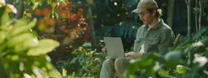 a landscaper analyzing website performance on a laptop while sitting in a garden.
