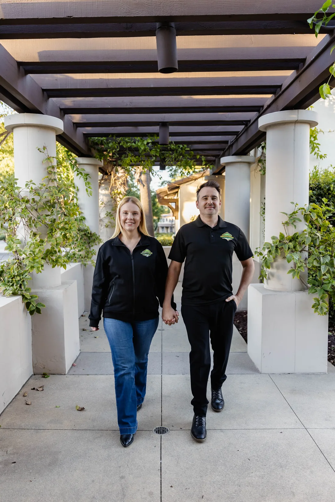 Josh and Chelle Blakeley walking through a garden pergola in LHCM team gear